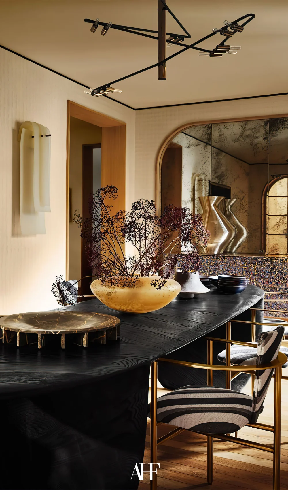 A maximalist dining room with a black table and decorative chairs. layering patterns and textures with bold interior design.