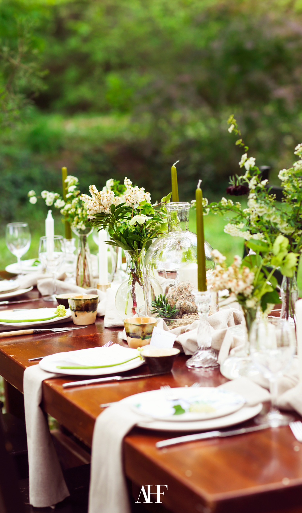 Neutral midsummer table setting with floral midsummer centerpiece. A beautiful wooden table in the nature.