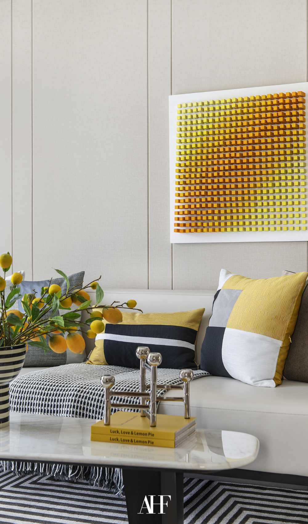 A yellow theme living room with neutrals and a beige sofa. A coffee table with a book and candlestick holders.