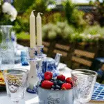 A beautiful midsummer table setting with blue tableware and a Floral midsummer centerpiece.