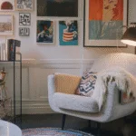 A maximalist living room with lots of art on the wall and a white armchair. Biold inteiror design.