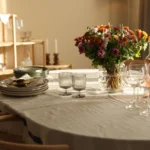 Stylish dinner setting with beautiful flowers and candle holders. A linen table cloth and some vine glasses.