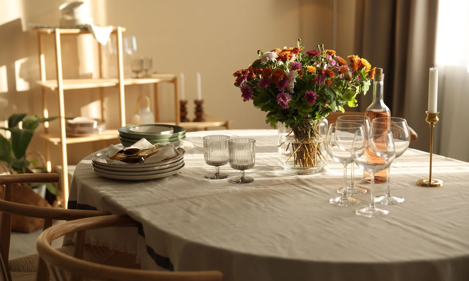 Stylish dinner setting with beautiful flowers and candle holders. A linen table cloth and some vine glasses.