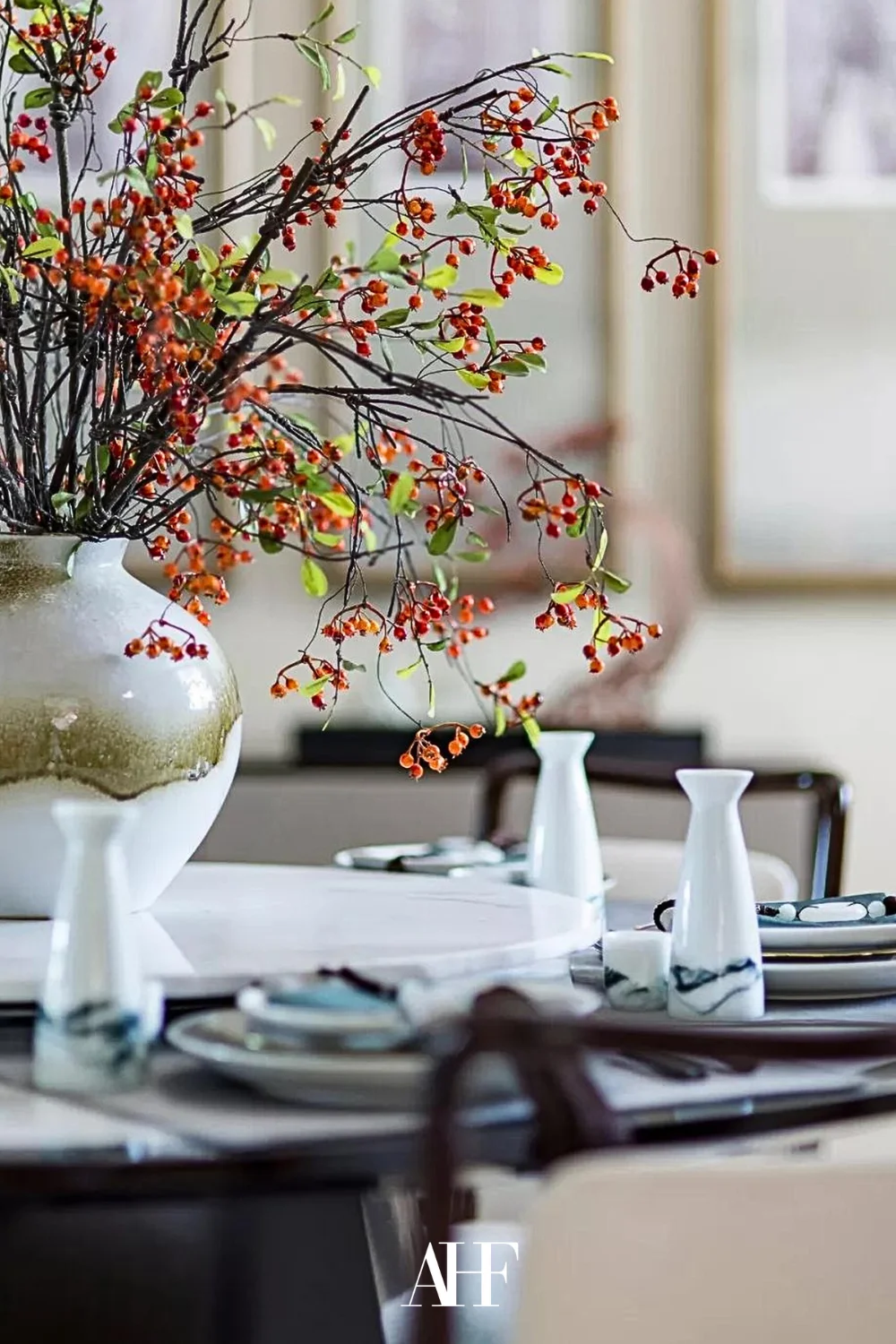 Beautiful table setting with a large ceramic vase with flowers in it. Decoraitons on the table.