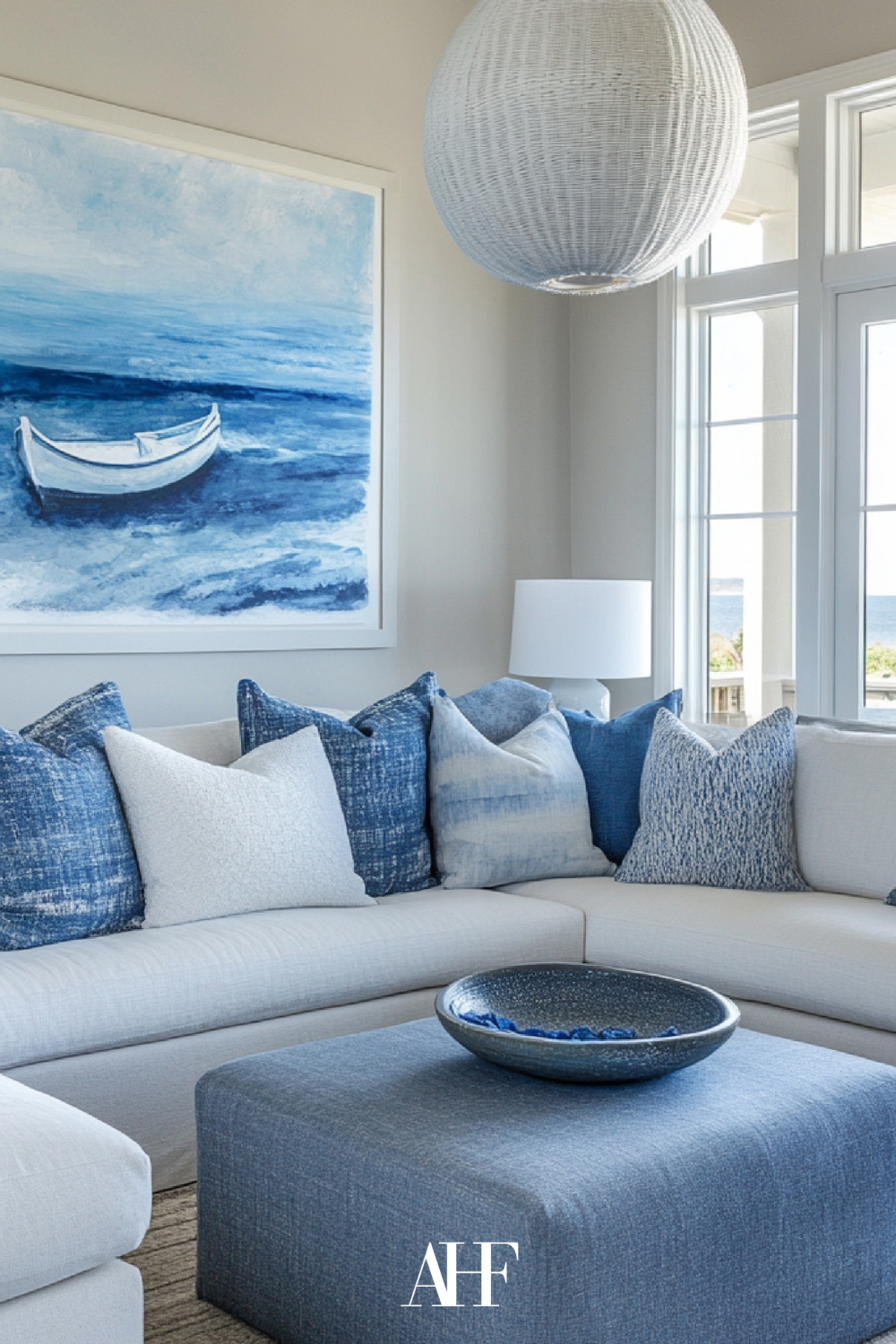 Coastal blue pillows and a coastal blue artwork. A white neutral sofa. coastal design living room.