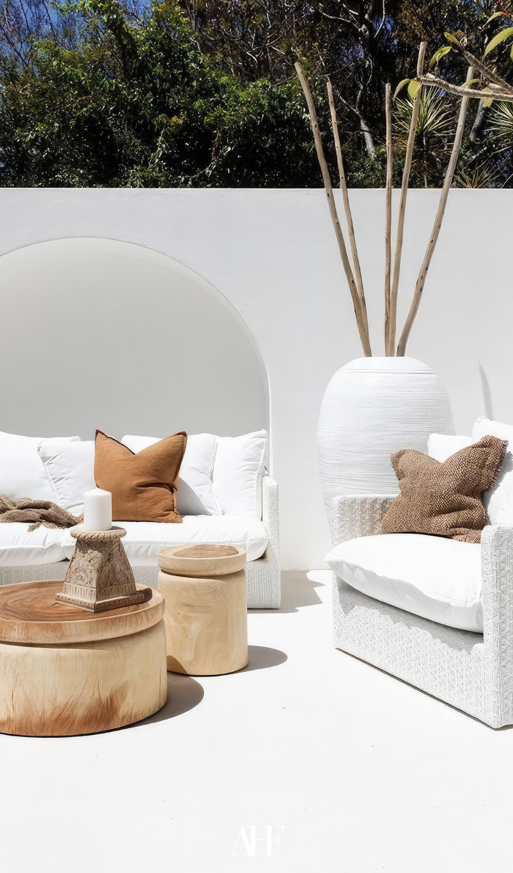 A white lounge ground and a light wooden coffeee table. Summer patio with white decor.