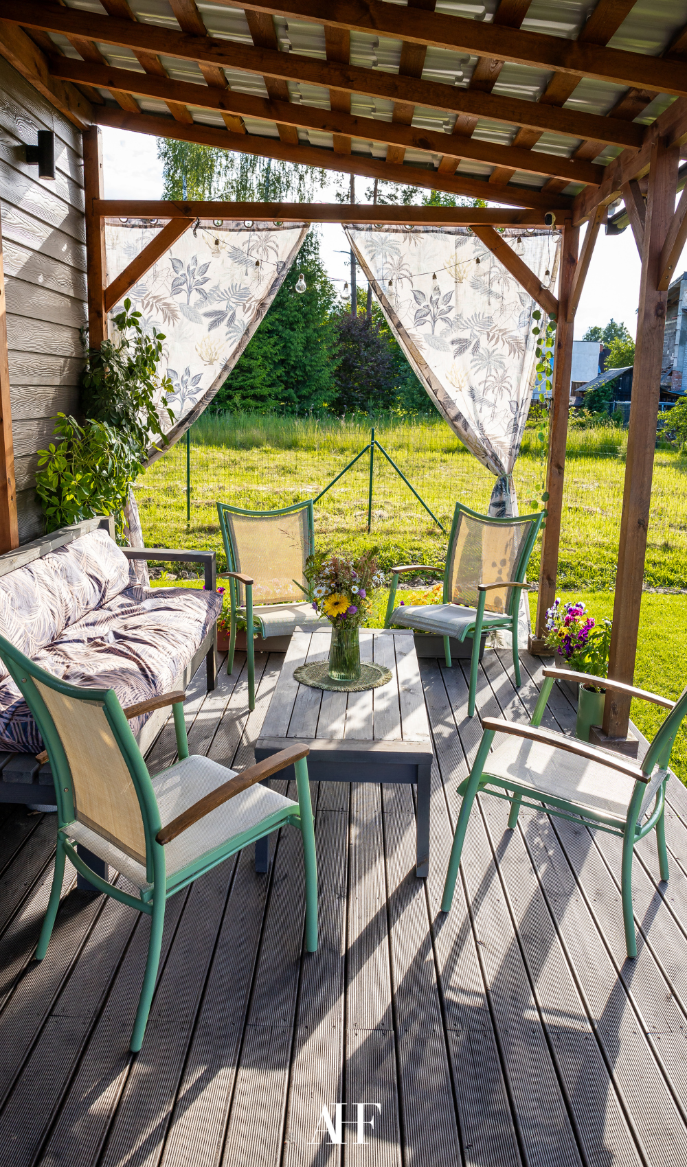 A small patio on the countryside with a couch and four armchairs, a coffee table in the middle.