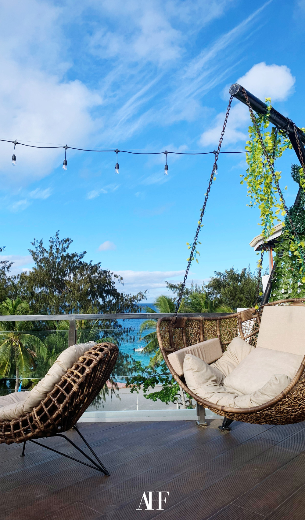 A hammock on a patio with a beautiful view of the woods and the ocean.