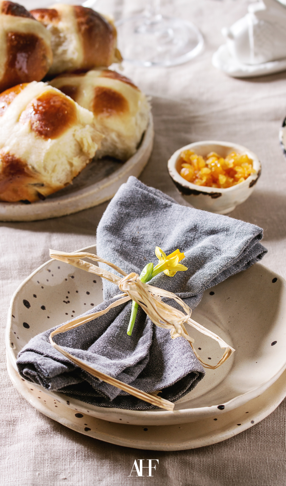 A table setting with a dotted table and some bread. A napkin on the plate.