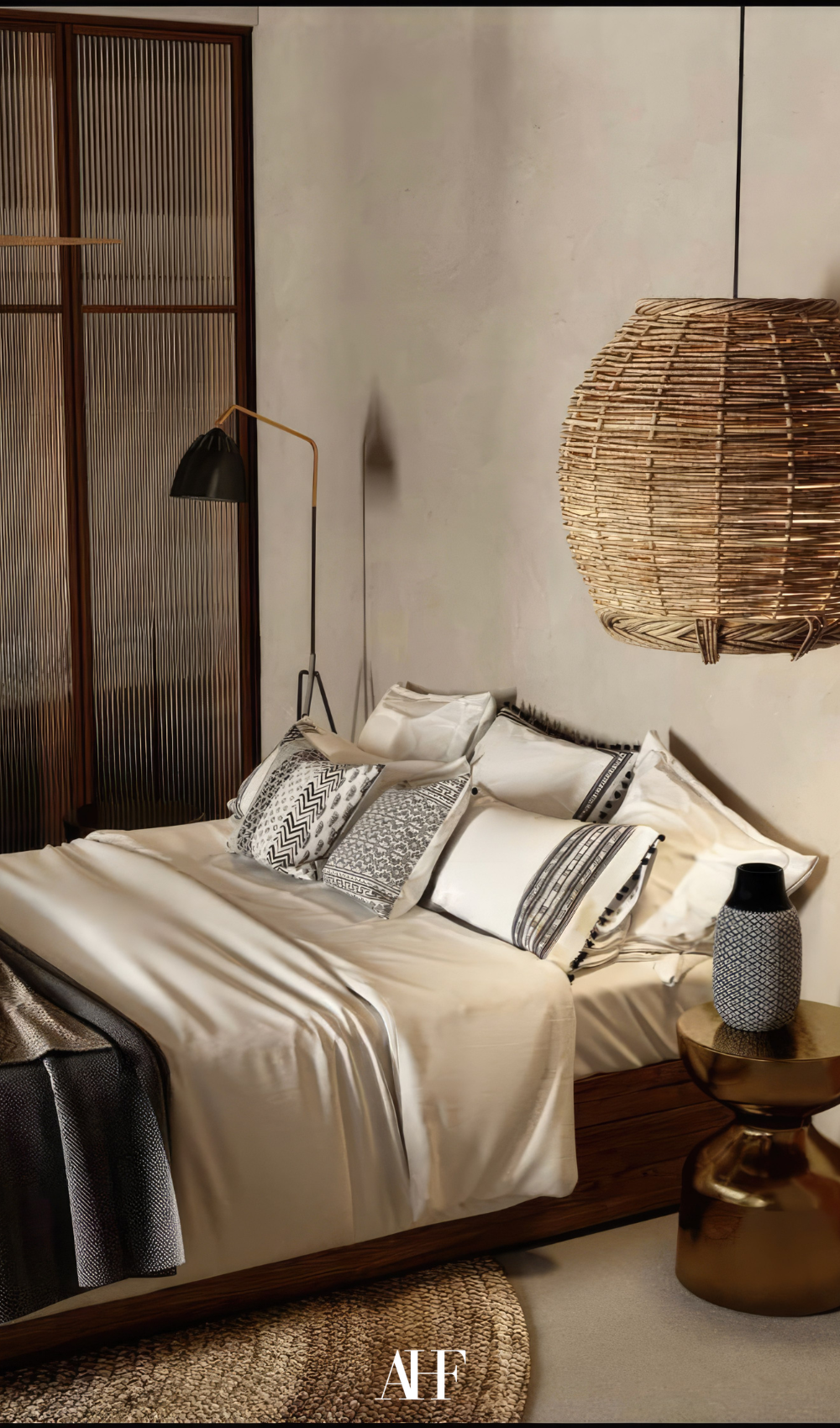 A beautiful modern earthy bedroom with silk bedding and earthy tones and a rattan ceiling lamp.