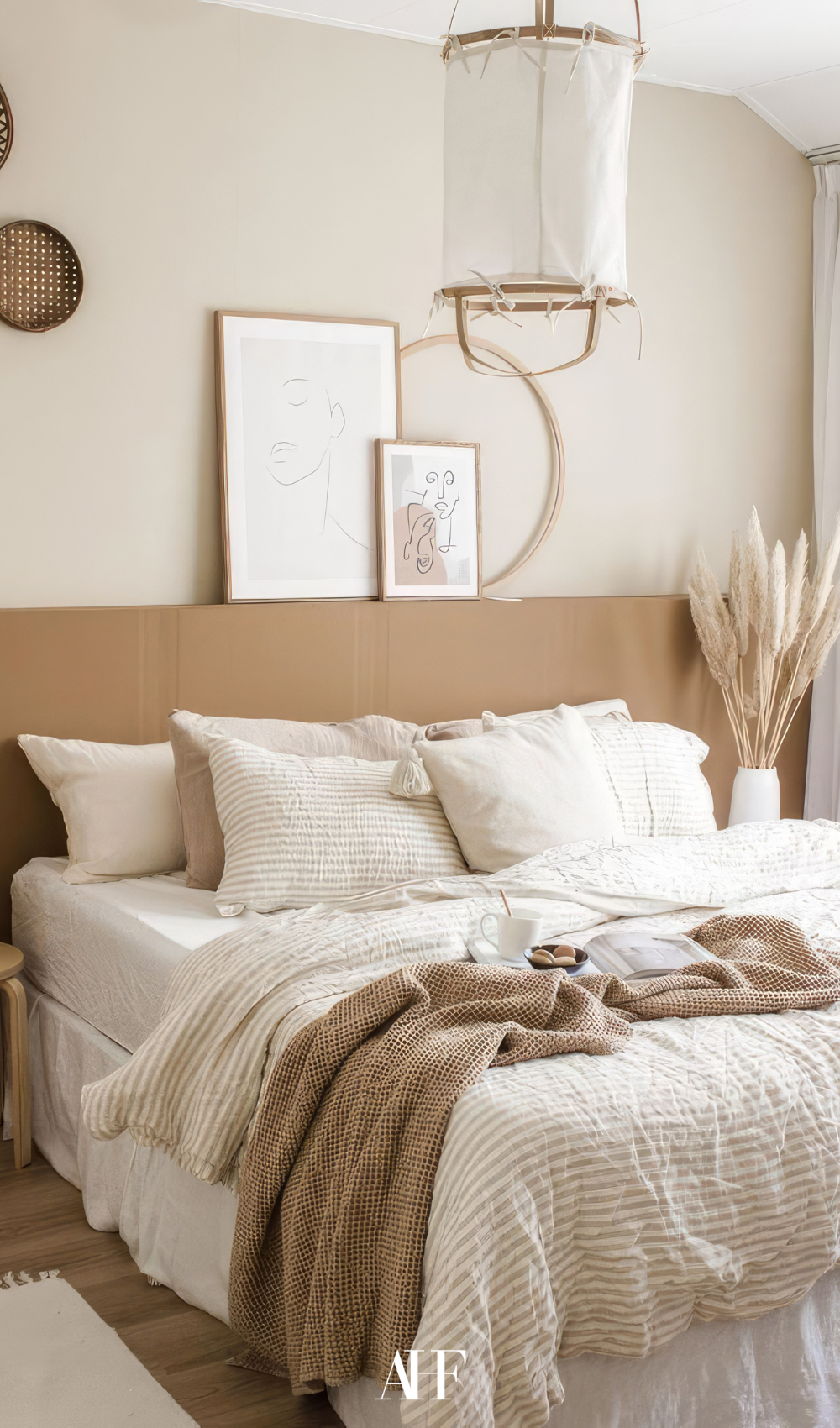 A cozy earthy bedroom with a beige bedframe, white bedding and beige detials.