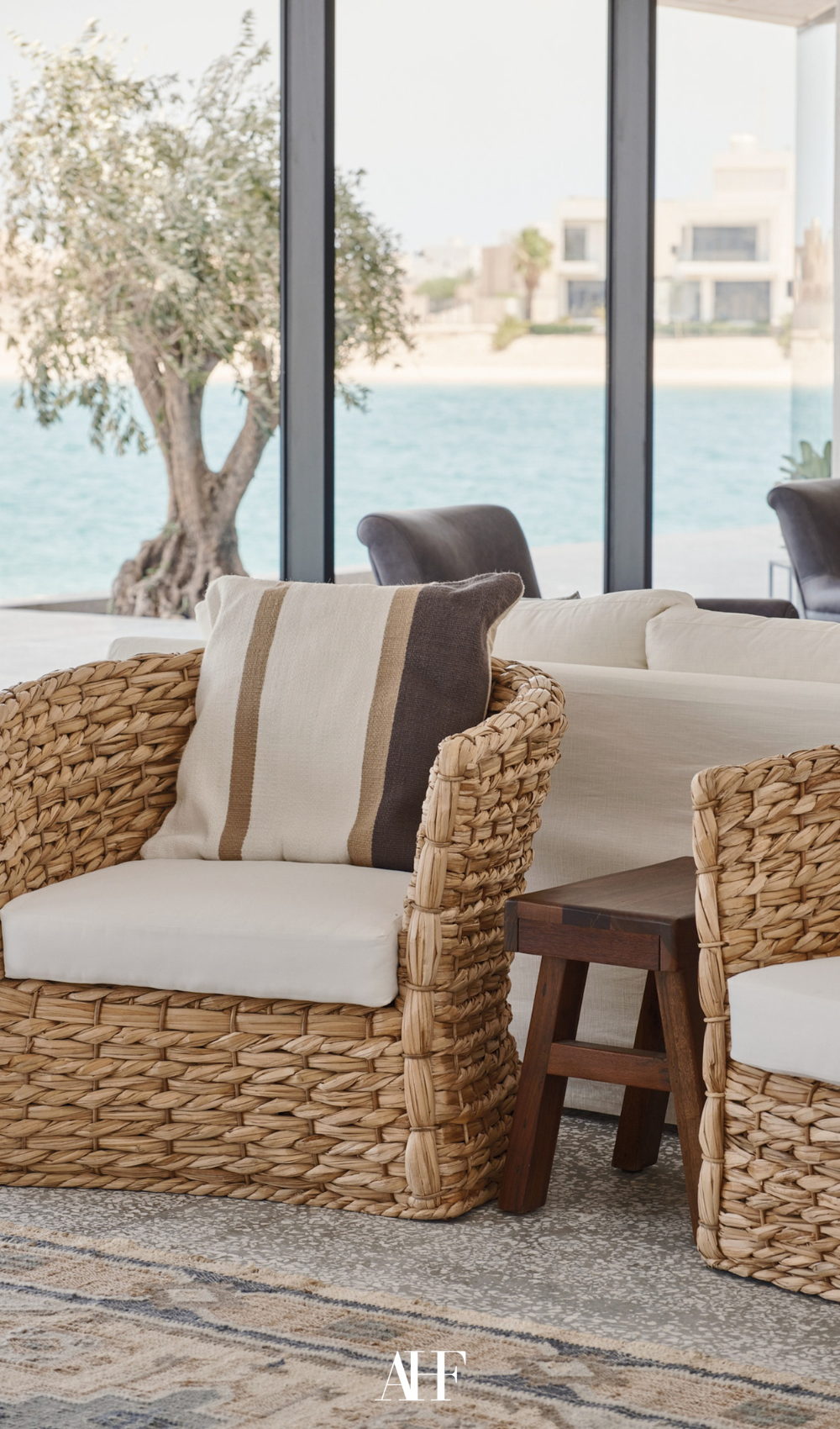 Natural Rattan Armchair with Cushion, a coastal sunroom with large windows.