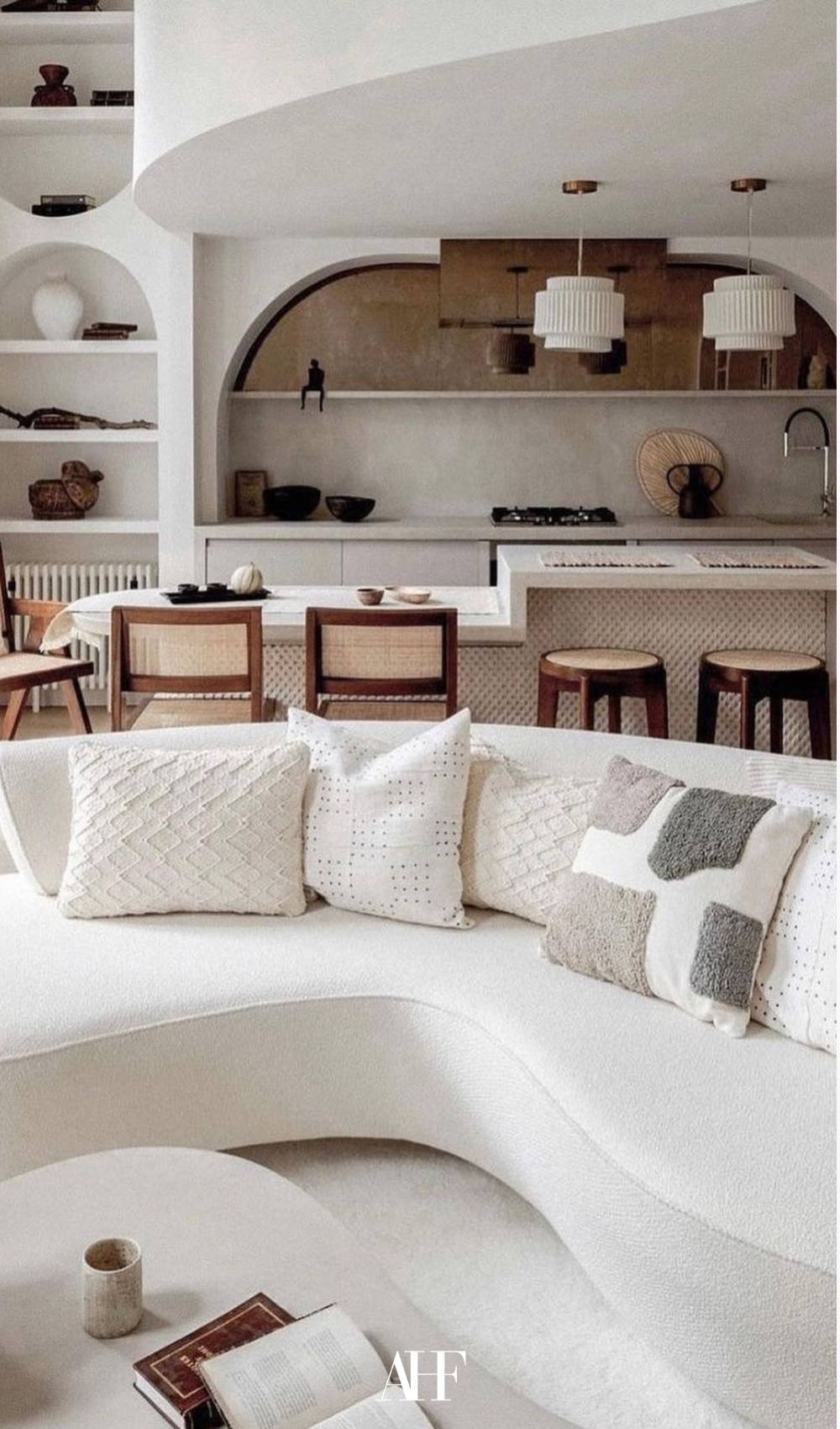 Japandi interior design. A large white sofa and a white coffee table. In the background is a neutral japandi kitchen.