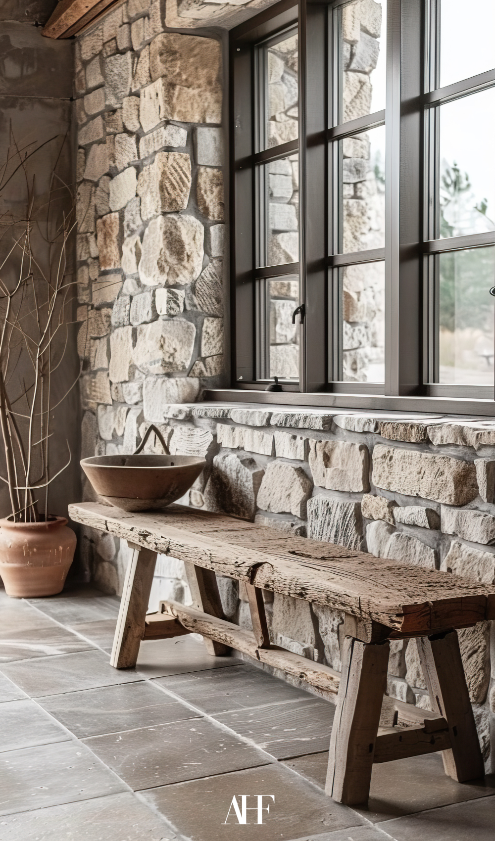 Rustic bench under a window by a stone wall. A decorative serving dish at the end of the bench.