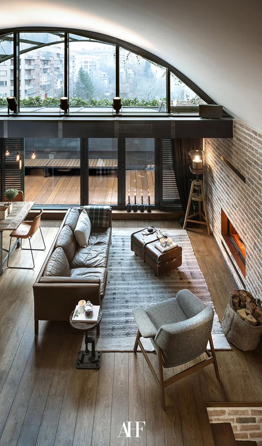 A beautiful industrial interior living room with a leather couch and an armchair. Brick wall and black details.