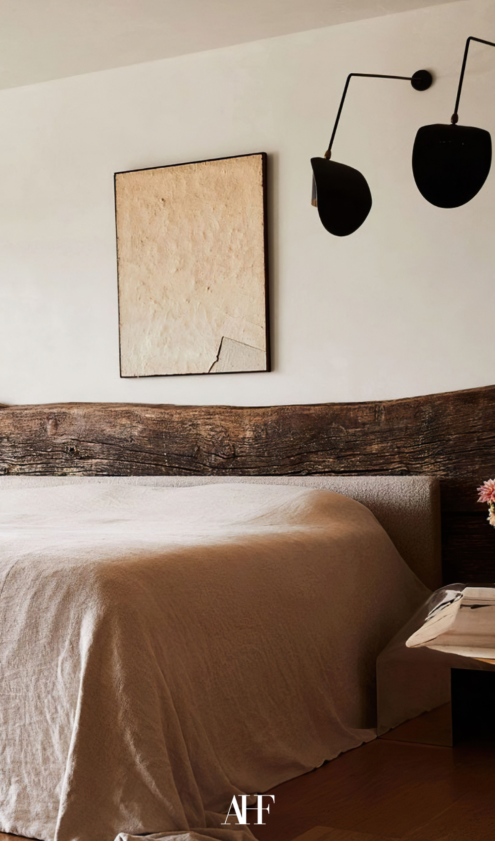 A beautiful earthy bedroom with a rustic wooden bed frame, a beige bedding and a bedside table .