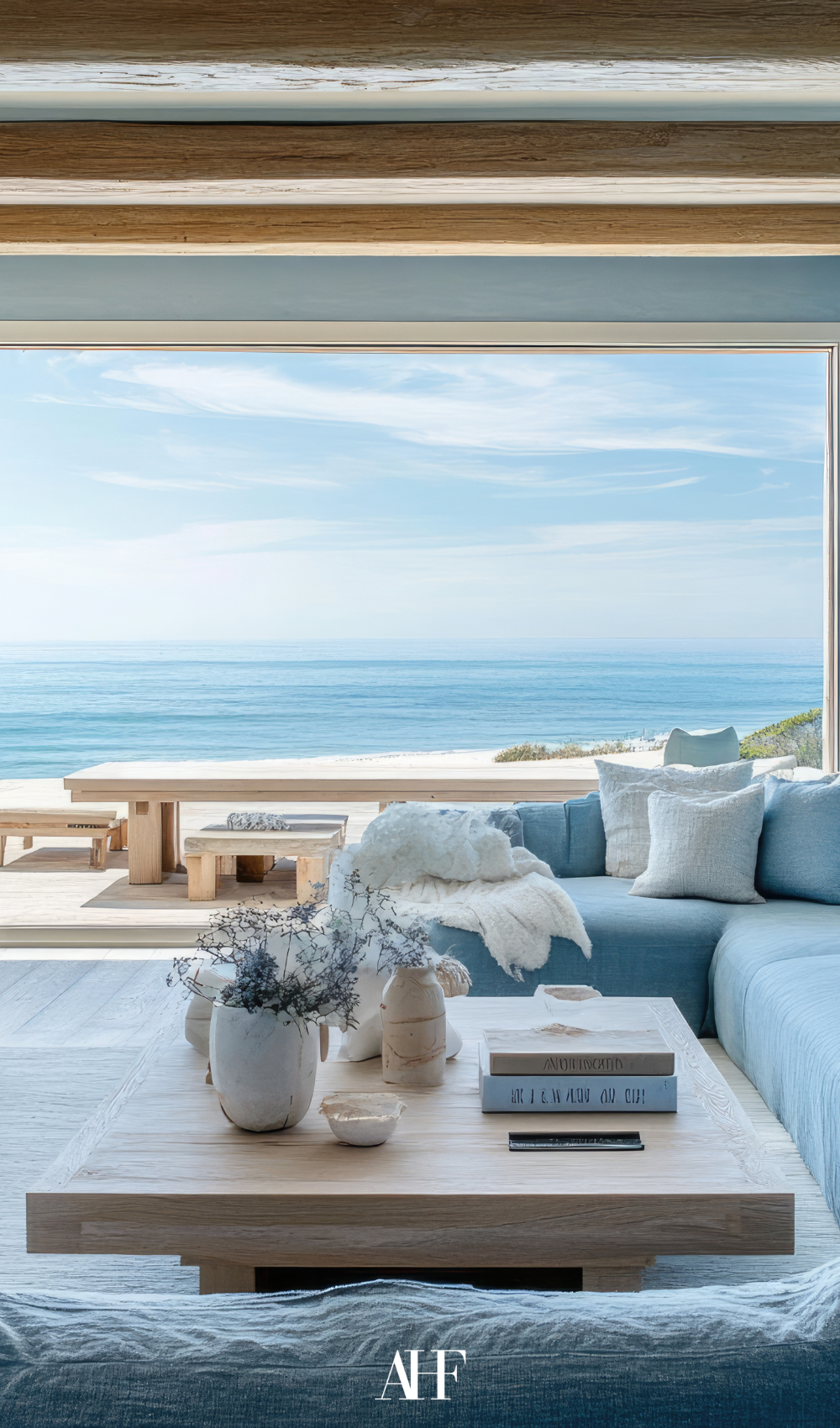 A beautiful coastal living room facing the ocean with a wooden coffee table and a blue sofa.