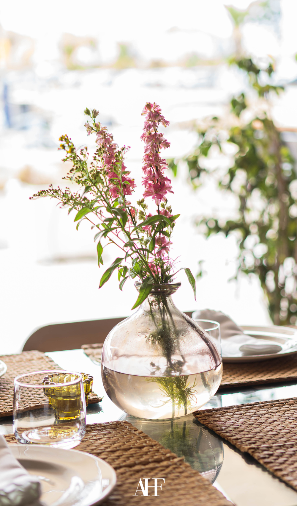 a summer table setting with a large floral centerpiece. dinnerware and coasters.
