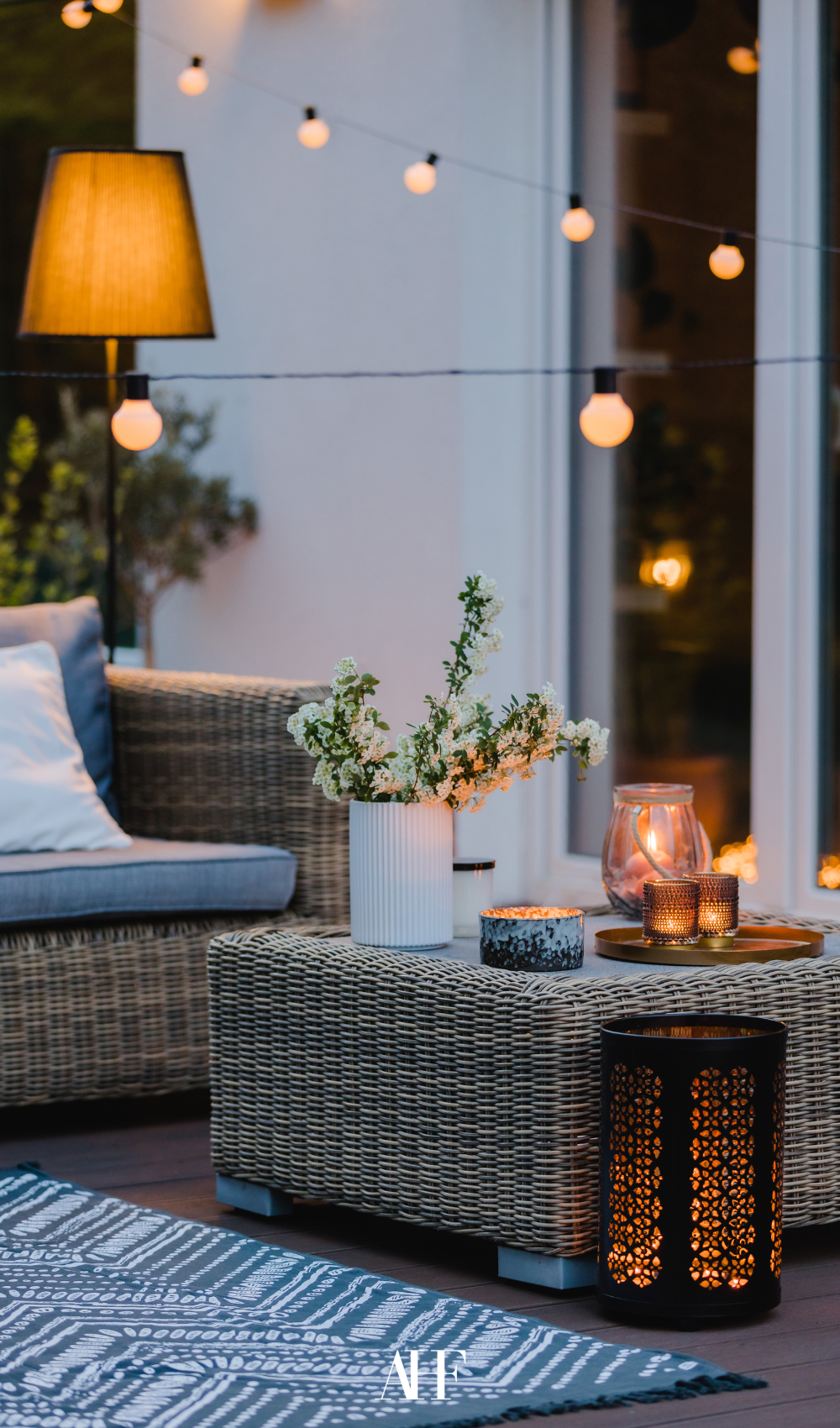 A cozy lit summer patio with rattan furniture and lots of different lights. Decorations.