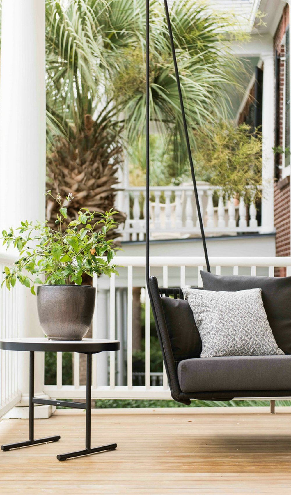 a minimalist small summer patio with a hanging couch and a coffee table with a plant on it.