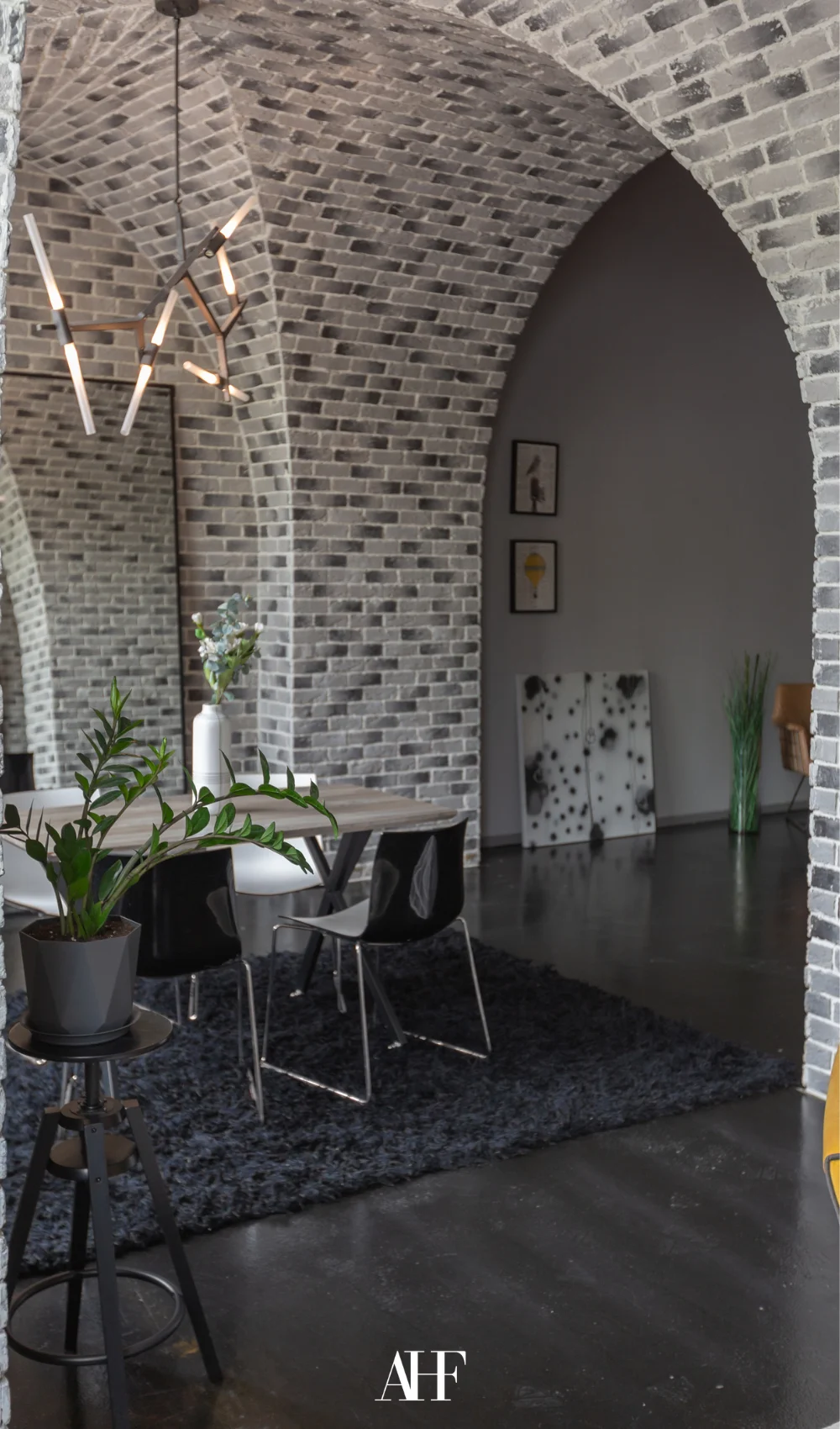 A industrial interior design dining room with brick walls, wooden dining table and leather chairs.