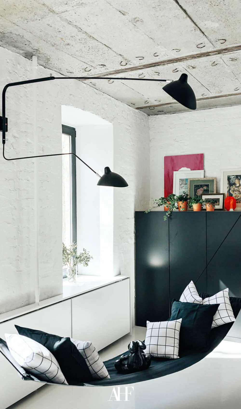 Industrial home with black details, concrete walls and a black sideboard, a black lamp.