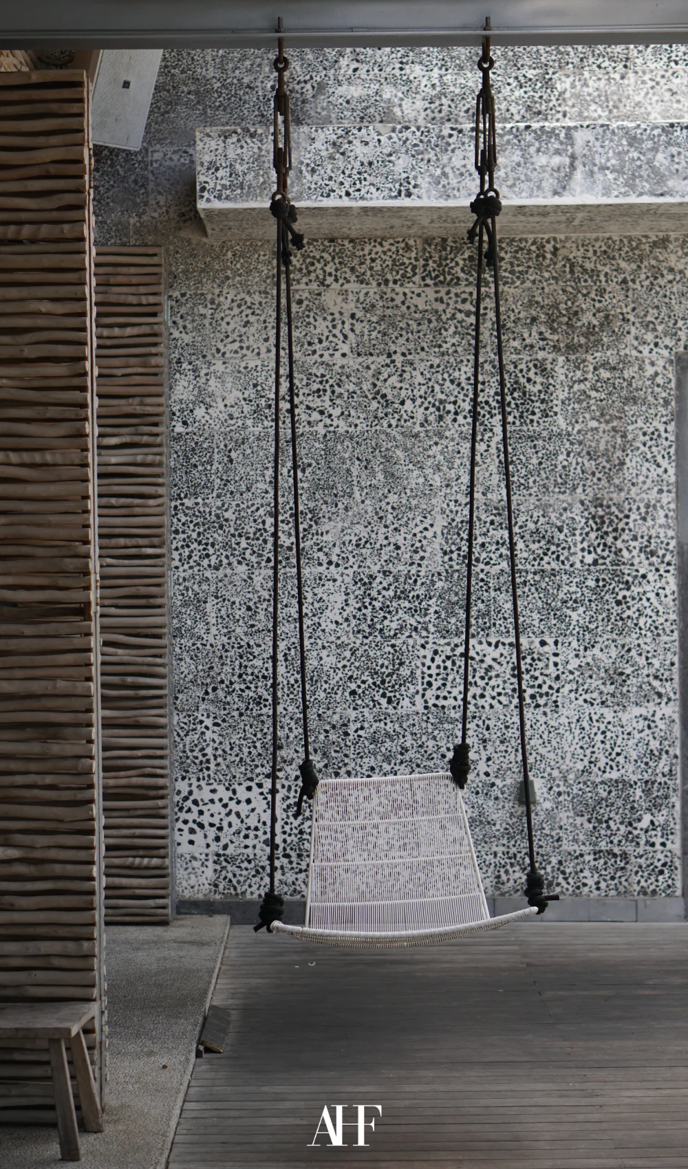 A brick wall and a swing. Grey colors and industrial interior design.