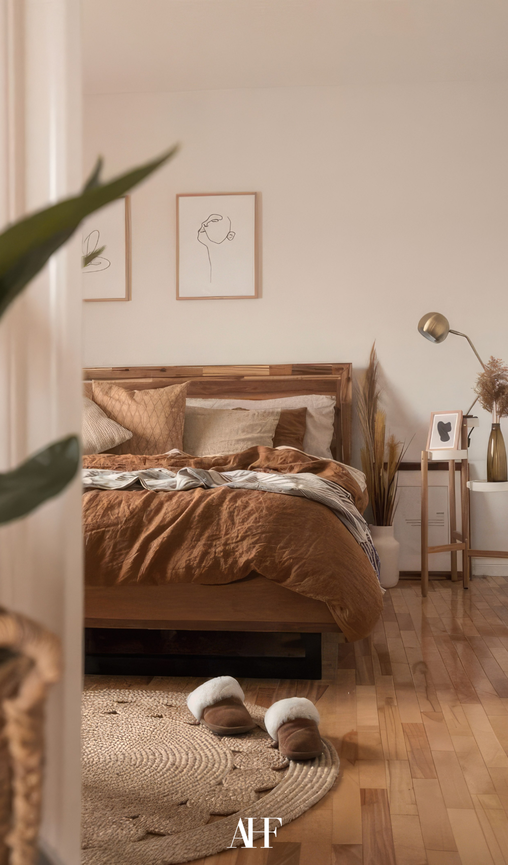 A cozy earthy bedroom with rust bedding and wooden floor. Decorations.