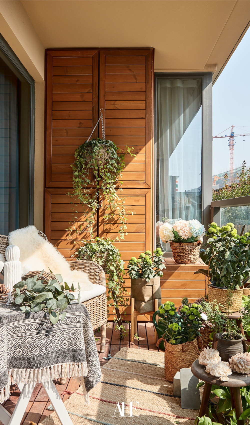 A wooden balcony with lots of plants and a white couch. Small summer patio.