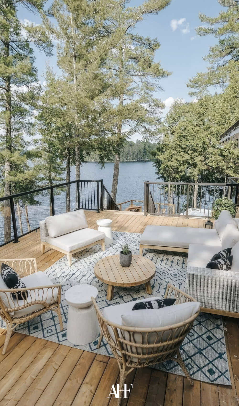 A swedish summer patio in front of a lake. A llight wooden lounge group with a wooden coffee table.