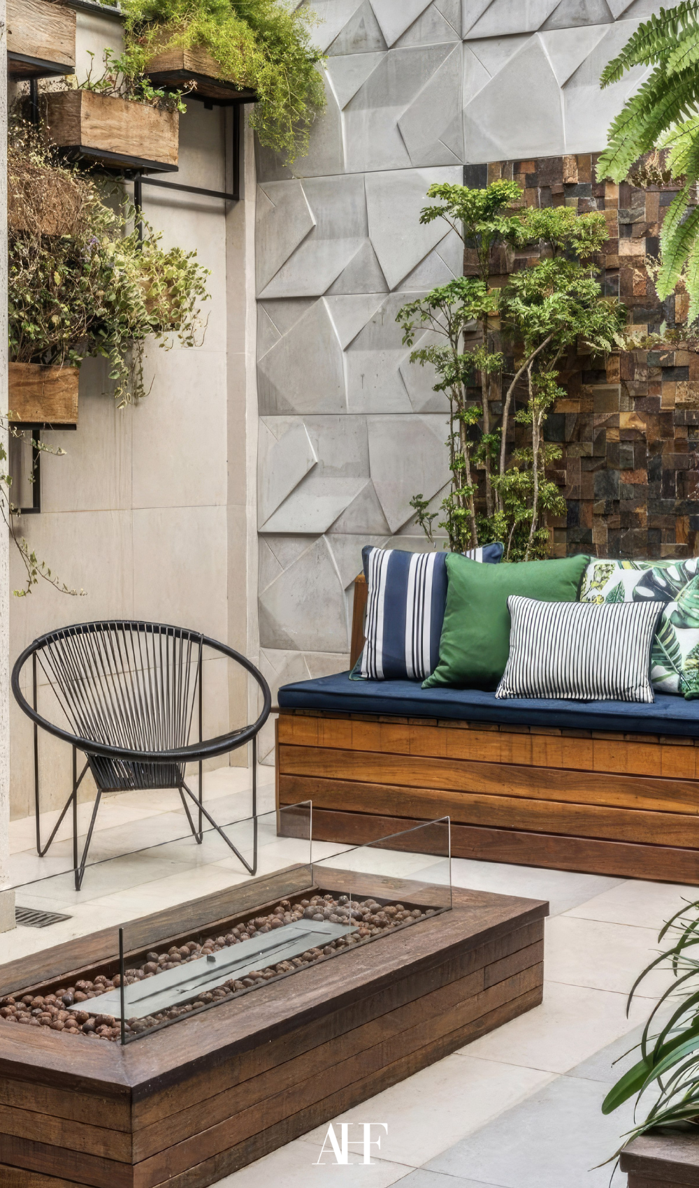A wooden couch with blue and green pillows, a black armchair and a fireplace in hte middle.
