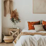 Earthy bedroom with rust pillow and neutral bedding, a wooden bedside table.