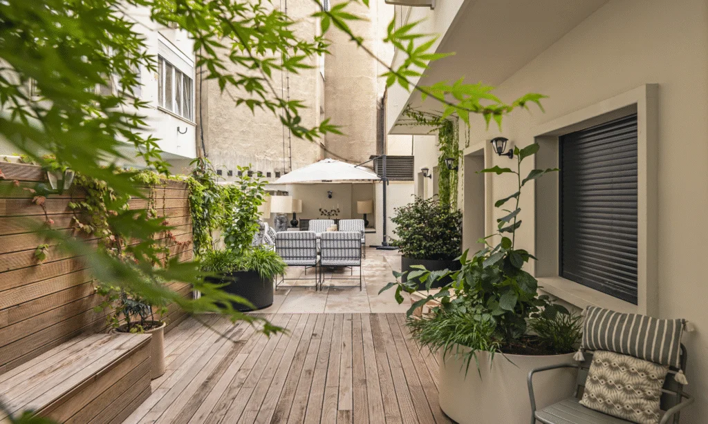 Summer patio in a city with lots of greenery and a wooden deck.