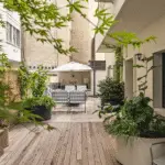 Summer patio in a city with lots of greenery and a wooden deck.