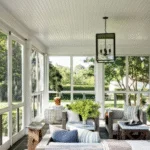 Beautiful sunroom with rustic furniture and a brick wall. Large white windows.