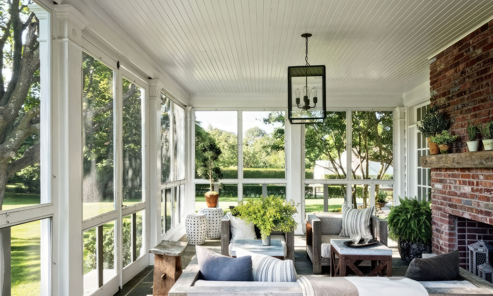 Beautiful sunroom with rustic furniture and a brick wall. Large white windows.
