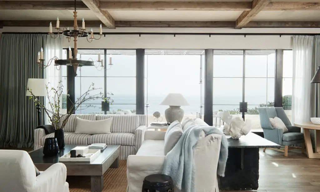 coastal living room with white sofas, coastal blue details and large windows facing the ocean.