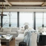 coastal living room with white sofas, coastal blue details and large windows facing the ocean.