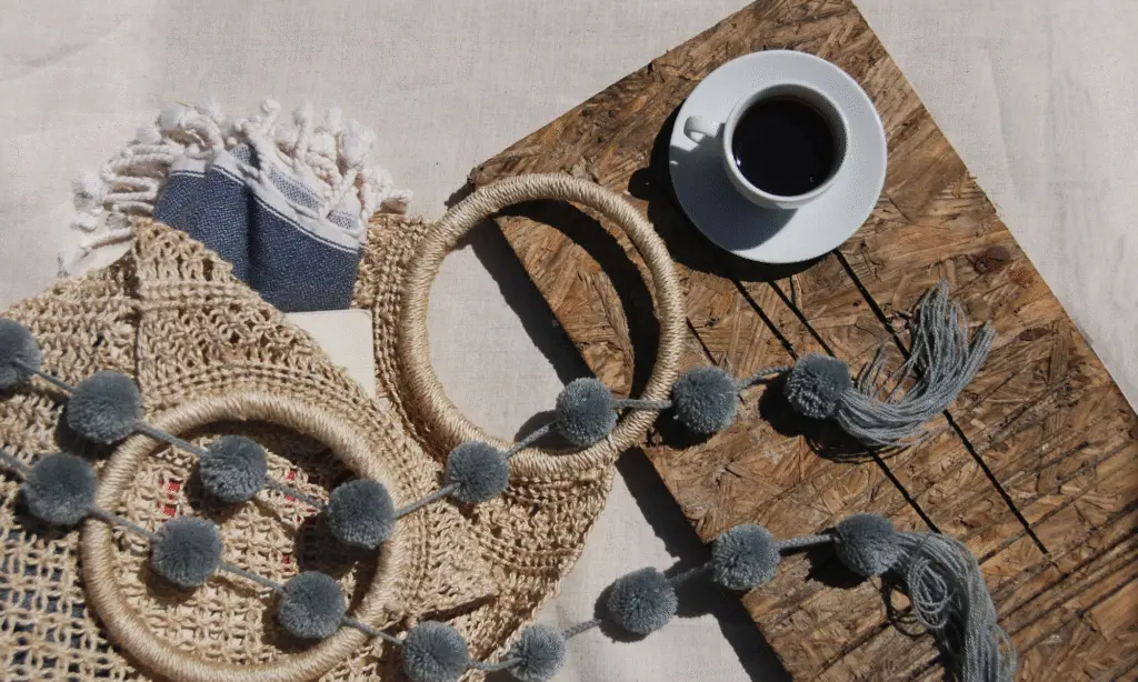 A summer picture of a cup of coffee, a wicker bag, some summer accessories.