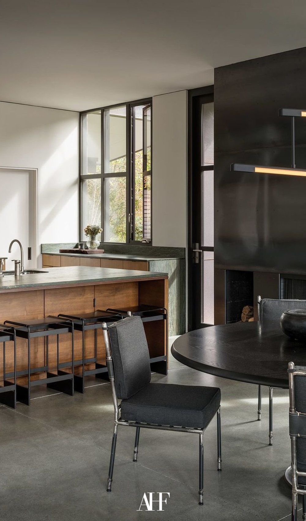 Industrial kitchen design with black details and wooden details. A black round kitchen table in front of a kitchen island.