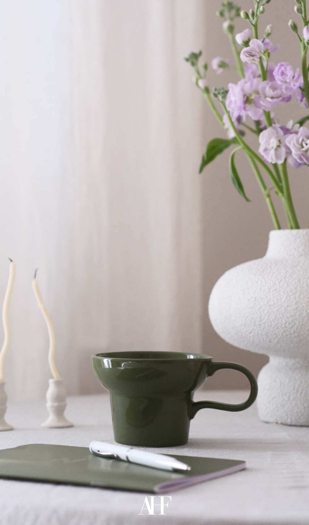 Aesthetic amazon home decor with a green cup, a white vase and a writing block. 