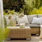 small summer patio with rattan furniture and lots of pillows and blankets.