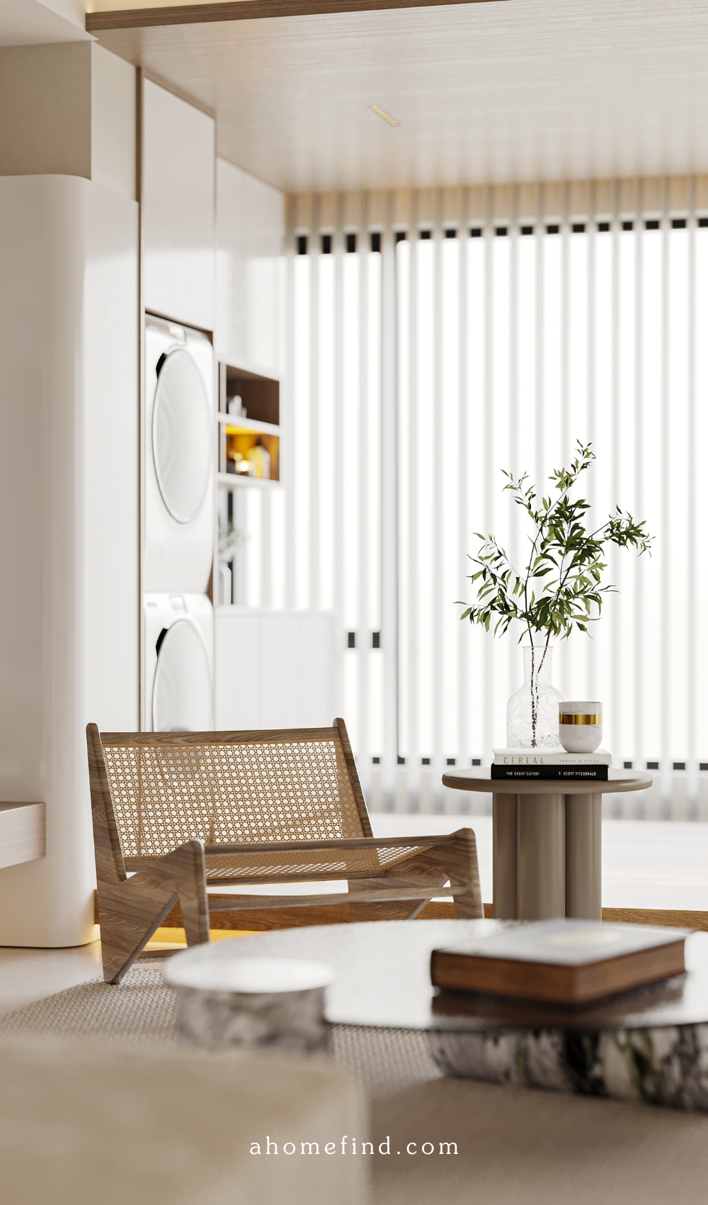A living room with a rattan armchair, a table with coffee table books, and a large window in the background.