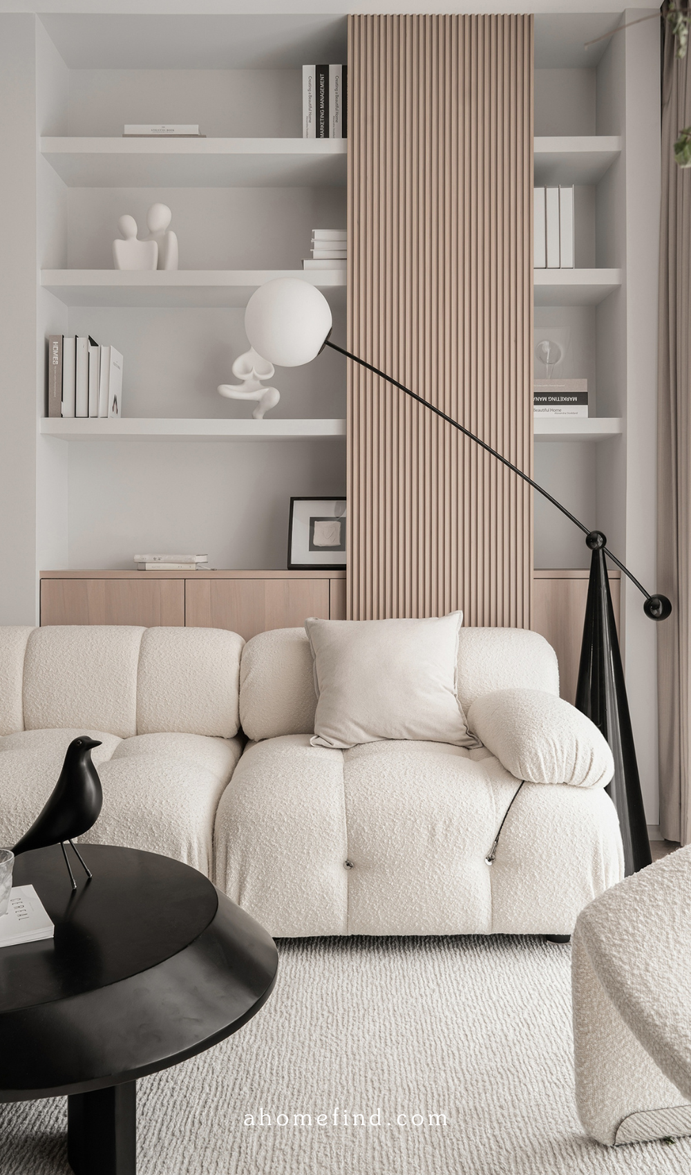 A Scandinavian living room with a beige sofa, a black coffee table, a white and black floor lamp and wooden details. 