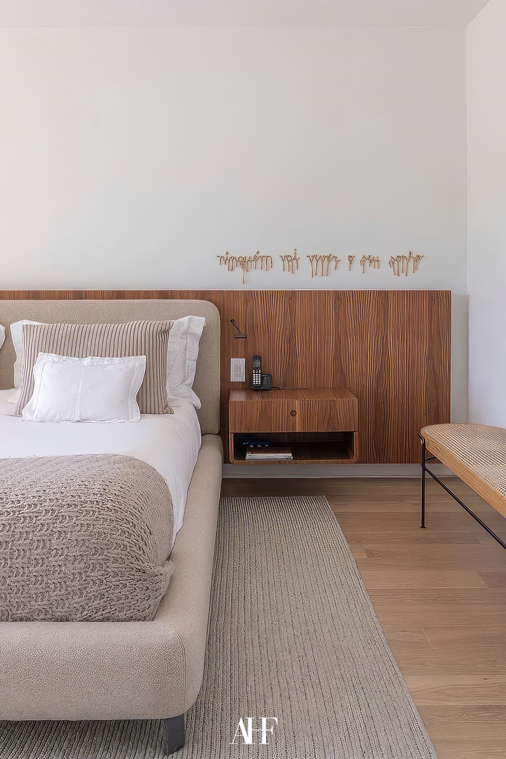 A beautiful bedroom color scheme with wooden panel as a bed frame, a neutral beige bed and neutral bedding. 