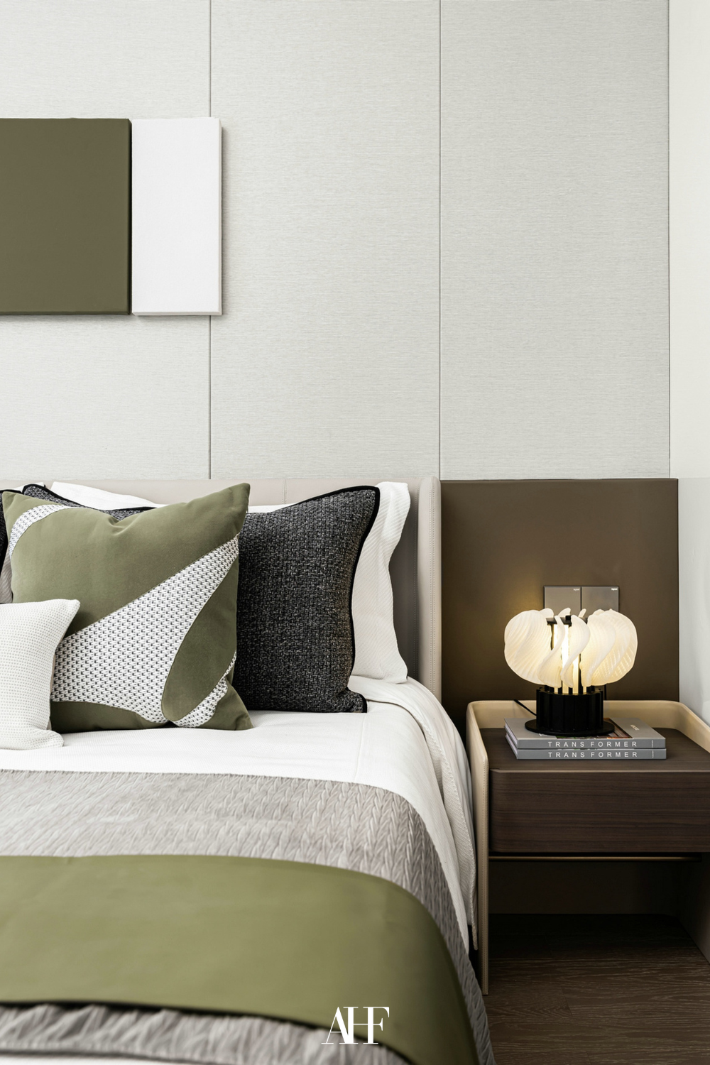 Beautiful bedroom color combinations with green and brown details and a neutral base. A bed with pillows and a green blanket. A dark wooden bedside table and beige walls. 