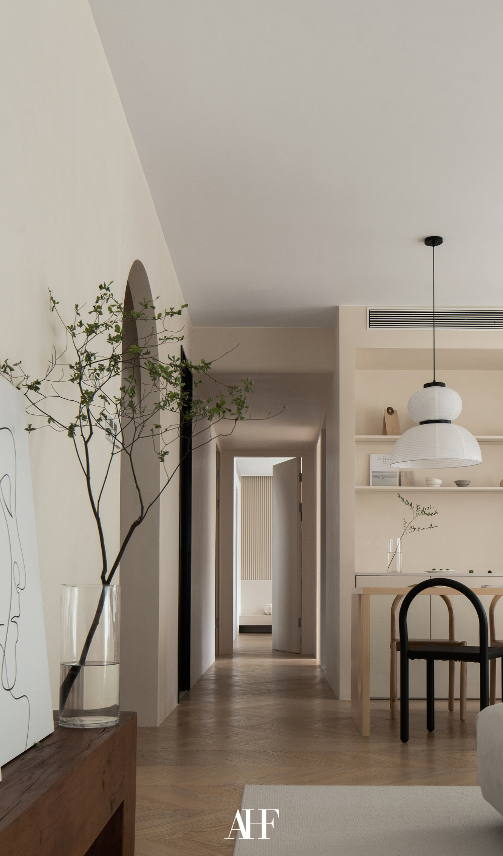 A beautifully decorated kitchen with a wooden sideboard with some decorations, a hanging ceiling lamp and som wooden chairs.