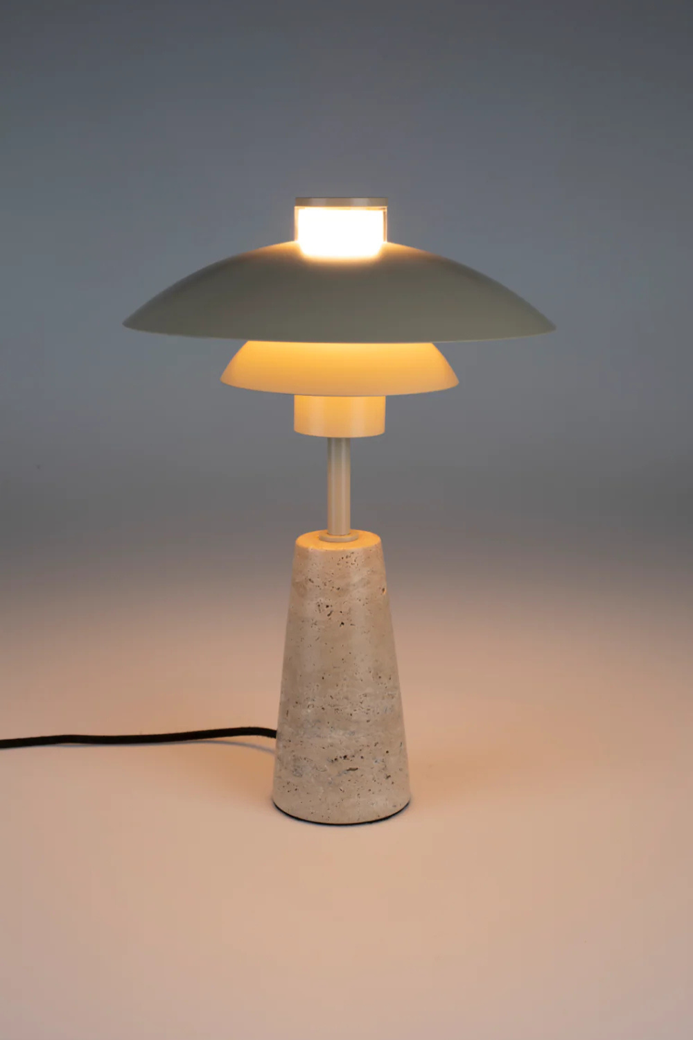 A modern beige table lamp with a marble foot. A white background and a soft light.