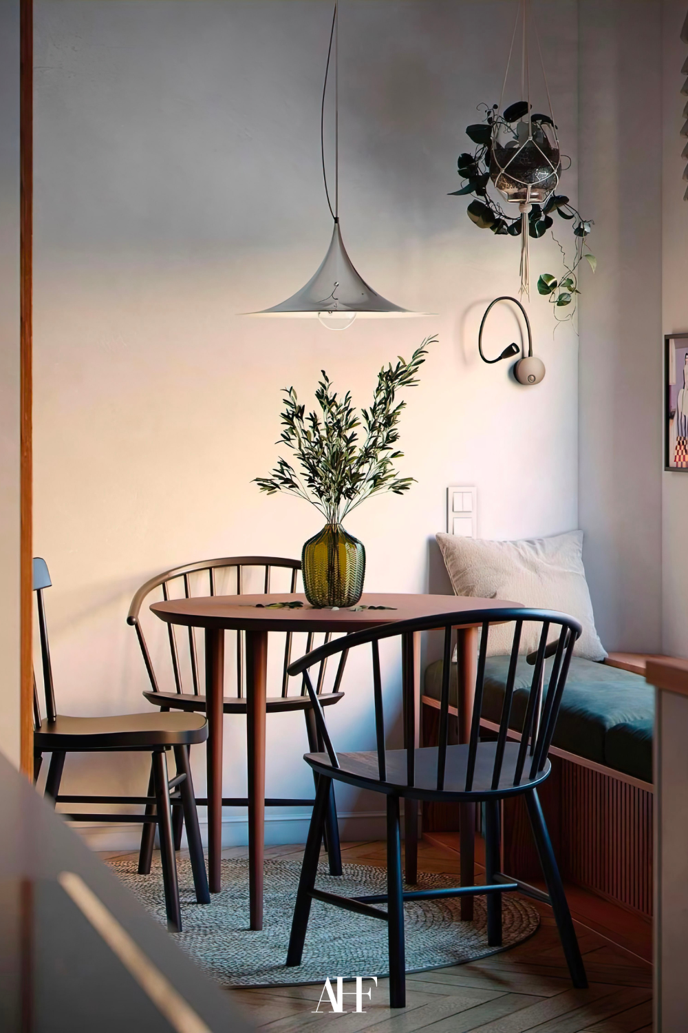 A beautiful dining room with a round wooden dining table and beautiful mid century modern interior design style inspired dining chairs. A beautiful vase on the table and a hanging ceiling lamp.