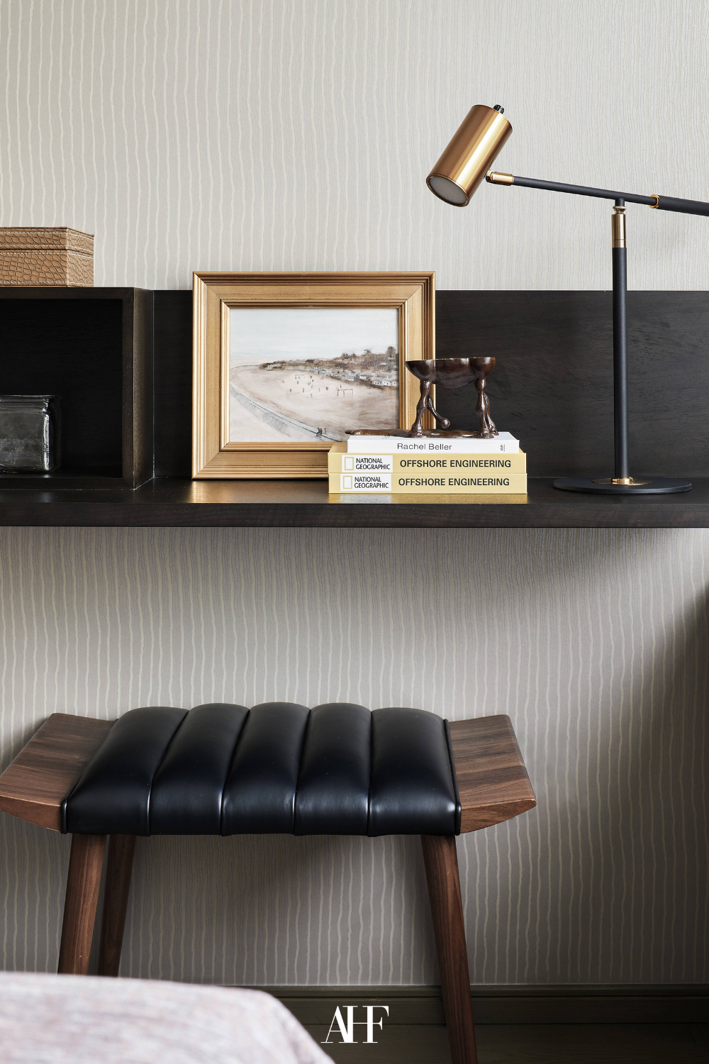 A leather chair and a dark wooden desk with a table lamp on it. A vintage modern interior design inspired room.